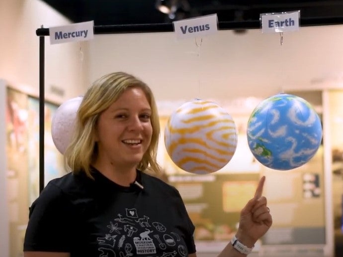 An educator points at a globe representing earth in our solar system.