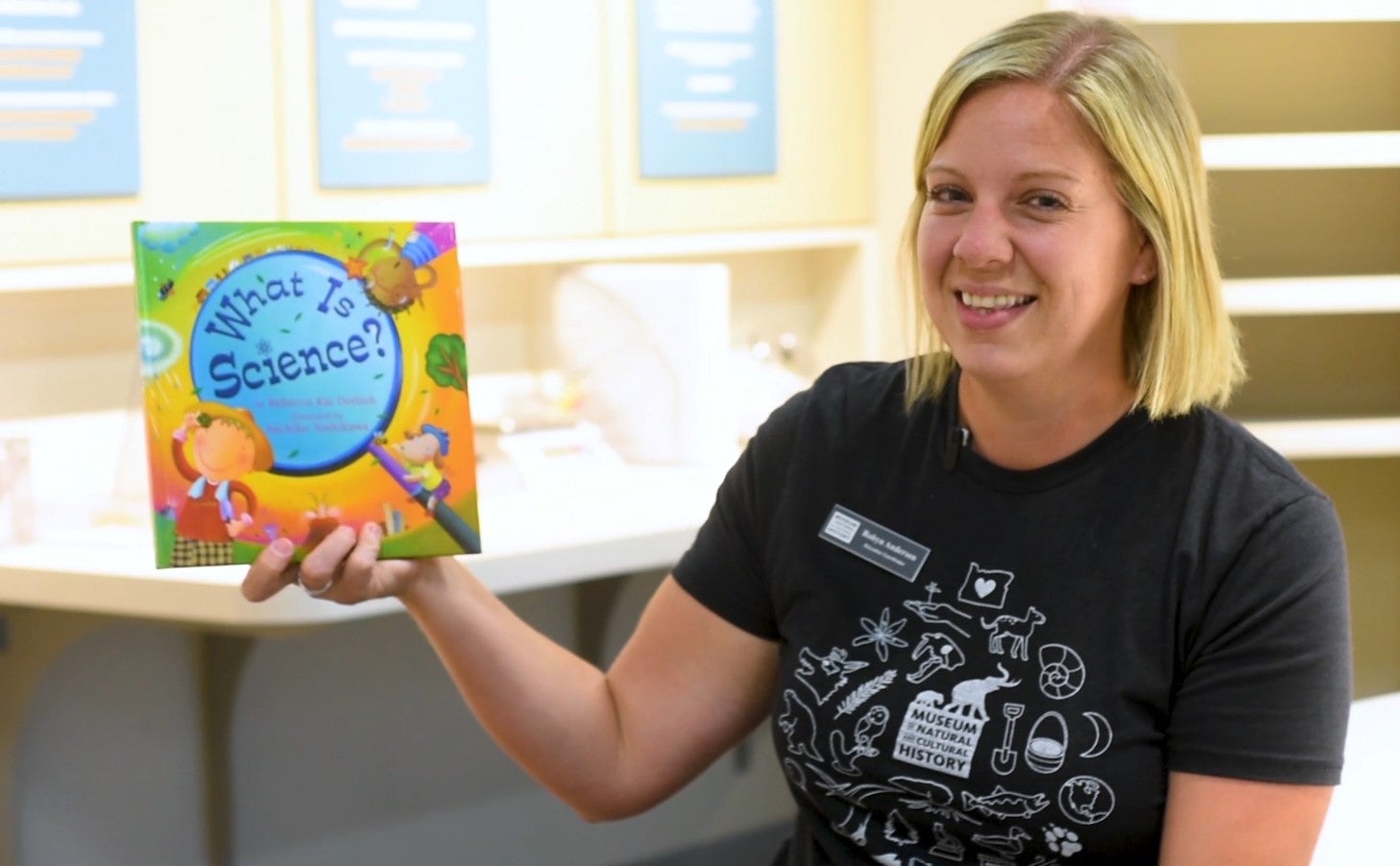 An educator holds up a book entitled What Is Science?