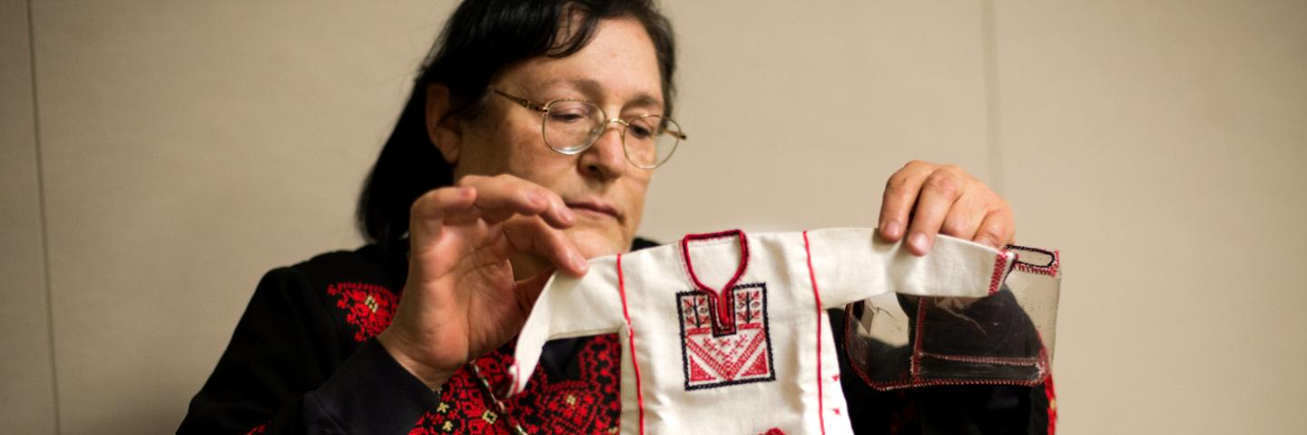Feryal holding up a completed piece of embroidery