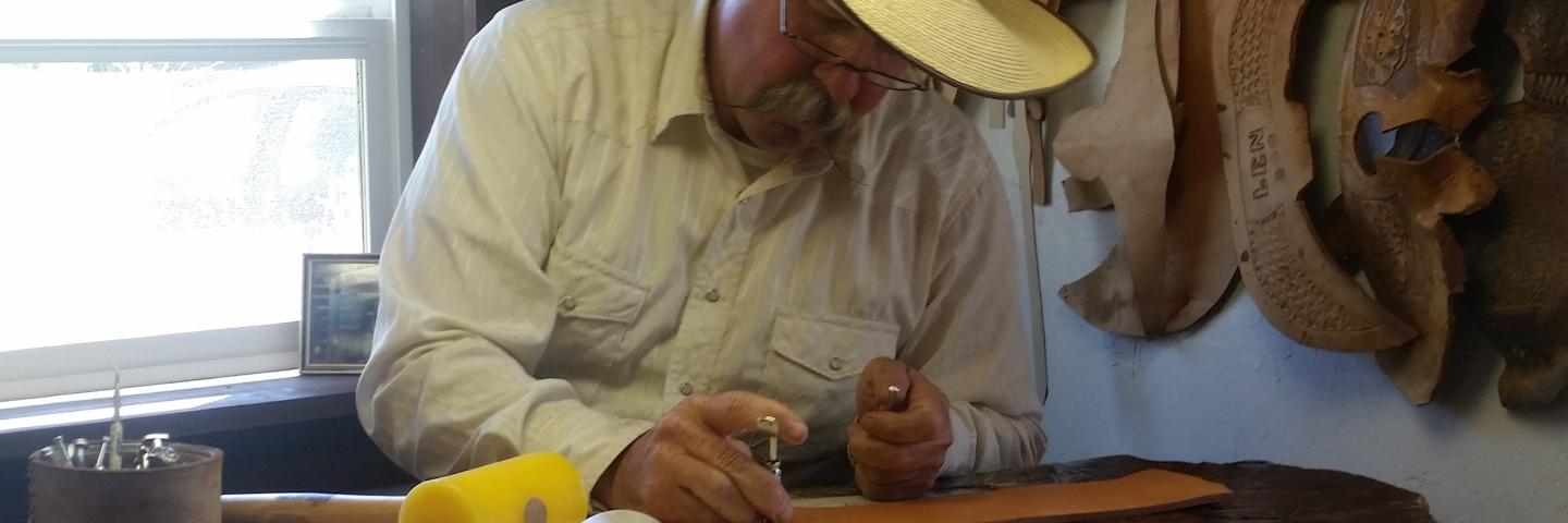 Len Babb working on a tan piece of leather with a mallet