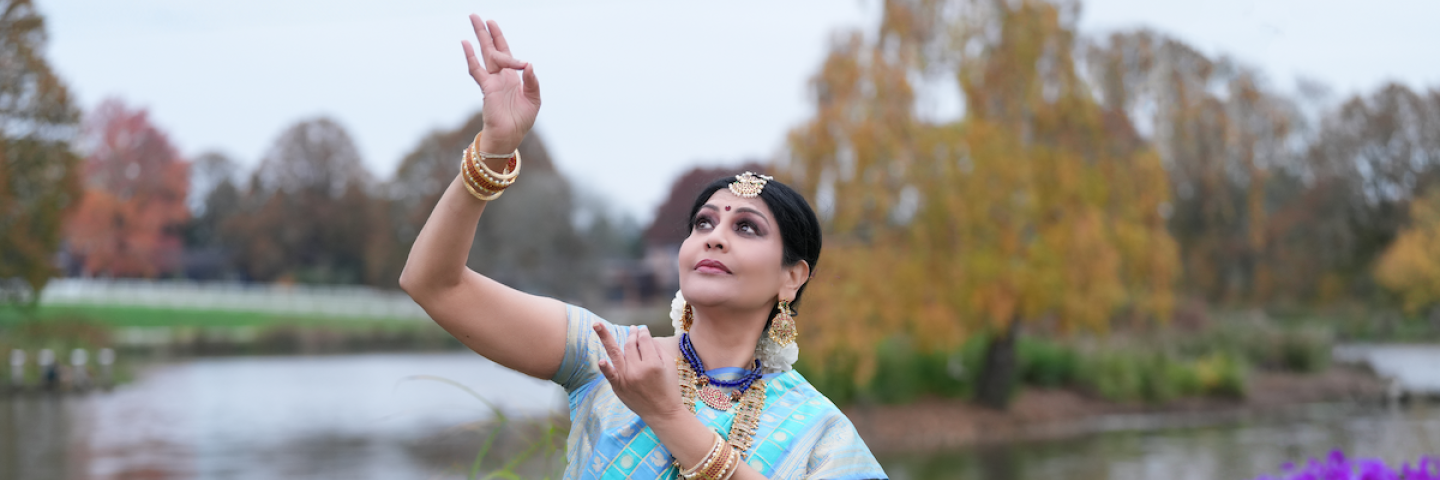 Jayanthi dances in front of a pond.