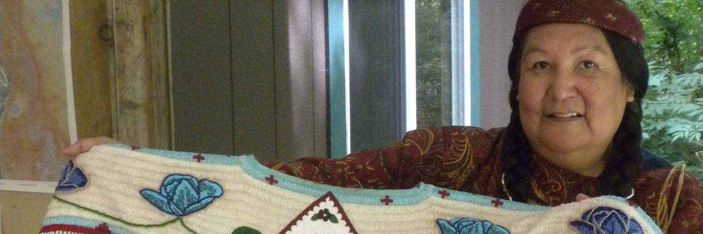 Roberta Kirk holding up one of her beaded dresses