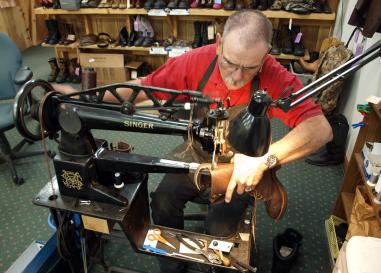 Man fashions a cowboy boot on a Singer sewing machine