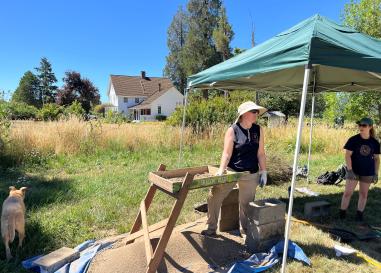 Archaeology students work in the field in front of the Applegate house