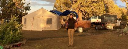 Yurt with person standing in front and a rainbow behind.