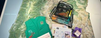 Clear backpack, green vest and activities sitting on a map of Oregon.