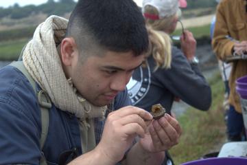 A person looks closely at a gnarly chunk of something they're holding